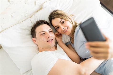 Romantic Couple Taking Selfie On Phone While Lying On Bed Stock Image