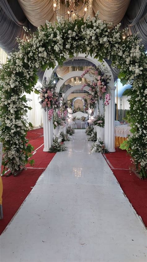 An Aisle Decorated With White Flowers And Greenery