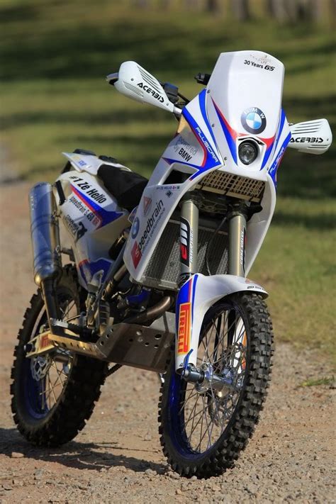 A White And Blue Motorcycle Parked On Top Of A Dirt Road Next To A Field