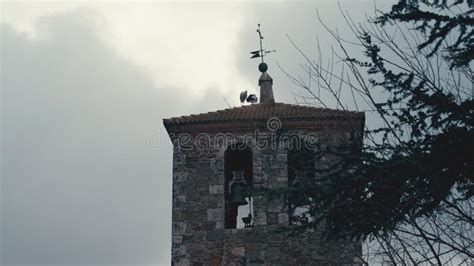 Two Storks Standing On Red Tiles Of Roof Of Bell Tower On Windy