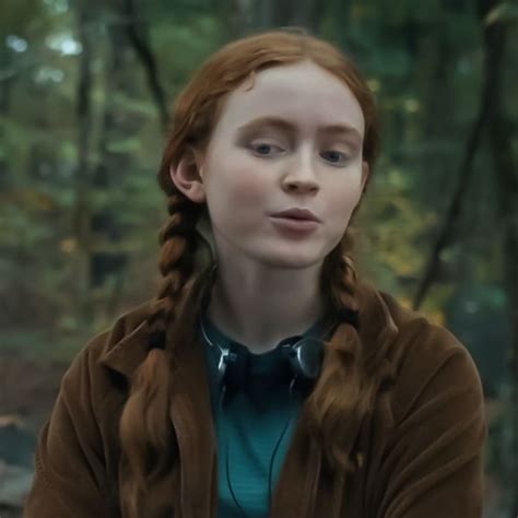 A Woman With Long Red Hair And Braids In A Forest Looking At The Camera