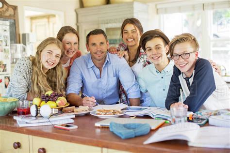 Group Of Teenagers With Mid Adult Man Sitting At Table In Dining Room