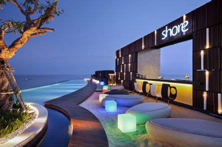 an outdoor lounge area next to the ocean at night with lights on it's sides