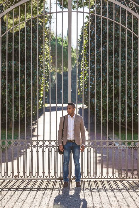 Black Businessman Standing In Front Big Gate In The Park By Stocksy