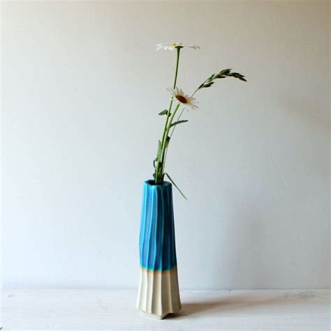 A Blue Vase With Flowers In It On A White Table Next To A Plain Wall