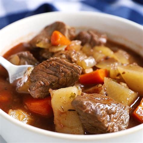 A Close Up Of A Bowl Of Stew With Meat And Carrots On The Side