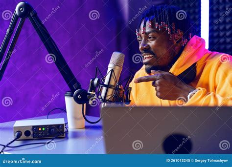 African Radio Host Sitting At Desk Recording In Studio With Microphone