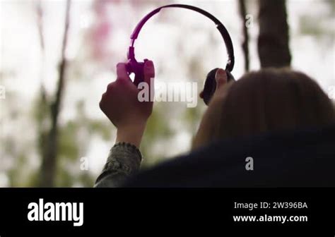 Silhouette Of Woman Putting Up The Headphones In The Forest Sun Light