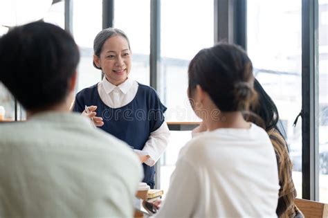 A Kind Mature Asian Female Professor Is Giving A Lecture To Her Students In The Classroom Stock