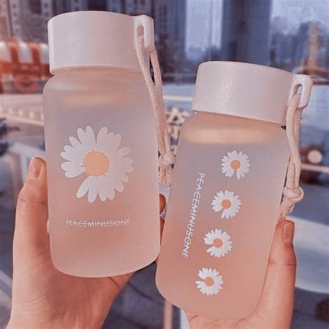 Two People Holding Up Water Bottles With Flowers On Them