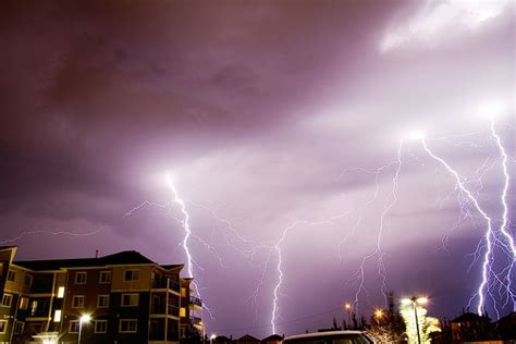 several lightning strikes in the sky above a city street at night with ...