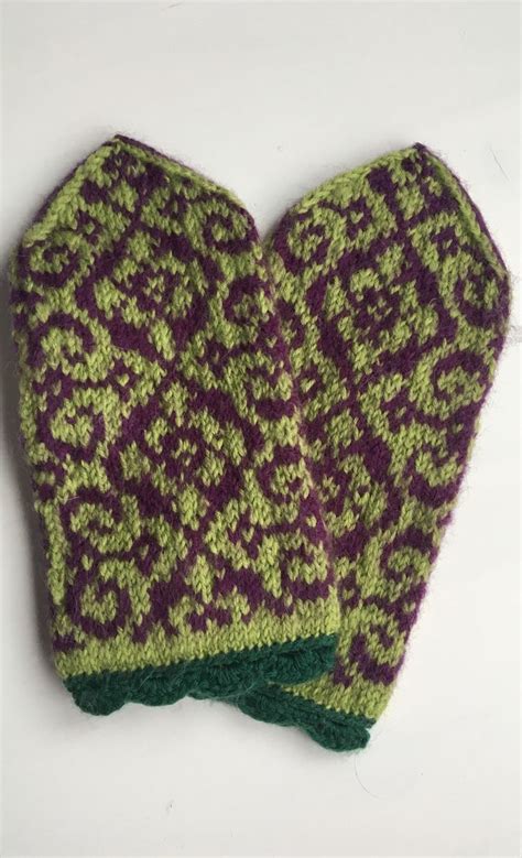 Two Knitted Mittens Sitting On Top Of Each Other