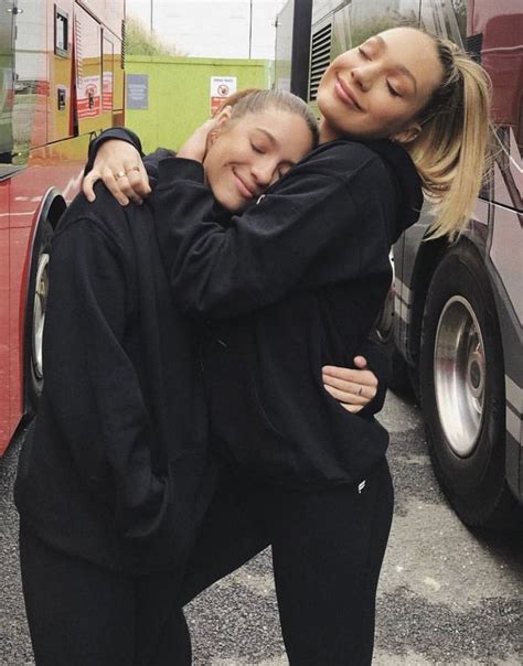 Two Women Hugging Each Other In Front Of A Bus