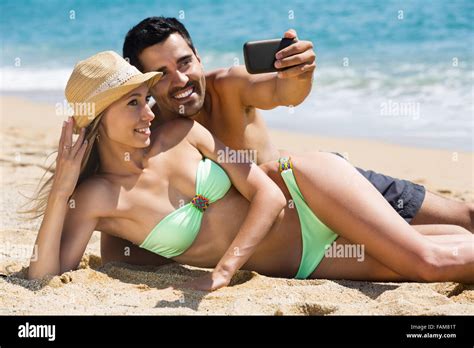 Happy Couple Relaxing On Beach Taking Selfie Picture With Camera