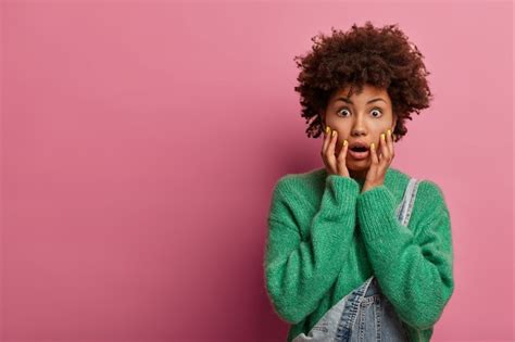 Free Photo Portrait Of Stunned Emotional Curly Woman Grabs Face