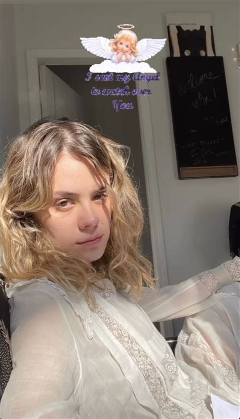 A Woman With Blonde Hair Wearing A White Shirt And Posing For A Photo In Front Of A Mirror