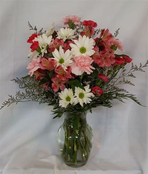 A Vase Filled With Lots Of Pink And White Flowers On Top Of A White