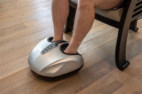 Man Relaxing While Having A Foot Massage On A Machine At Home Stock