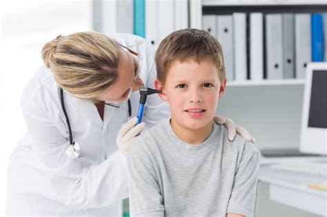 Niño siendo examinado por un médico con otoscopio Foto Premium