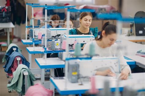 Costurera hermosa joven cose en la máquina de coser en fábrica Foto