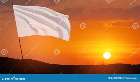 White Flag Waving In The Wind On Flagpole Against The Sunset Sky With