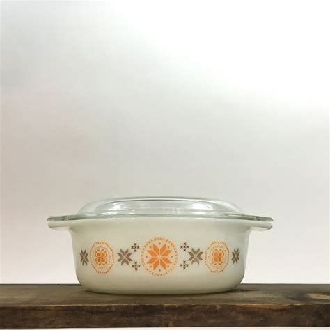 An Orange And White Casserole Dish Sitting On Top Of A Wooden Countertop