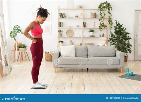 Frustrated Black Girl Standing On Weight Scales At Home Stock Photo