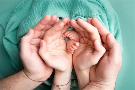 Mãos de pais e filhos em um fundo branco pernas de um recém nascido nas