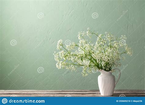 Flores Blancas En La Jarra Sobre La Pared Verde De Fondo Foto De