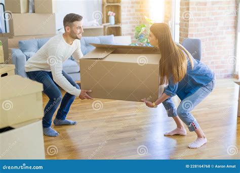 Beautiful Young Couple Moving To A New Home Holding Big Cardboard Box