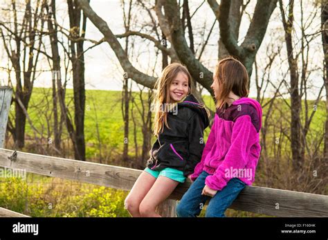 Girls Sitting On Fence Talking Stock Photo Alamy