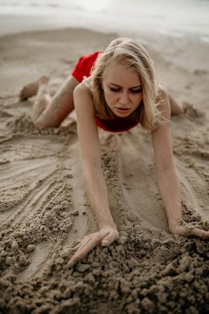 Una Chica Con Un Vestido Rojo Dibuja En La Arena Blanca Del Mar Foto