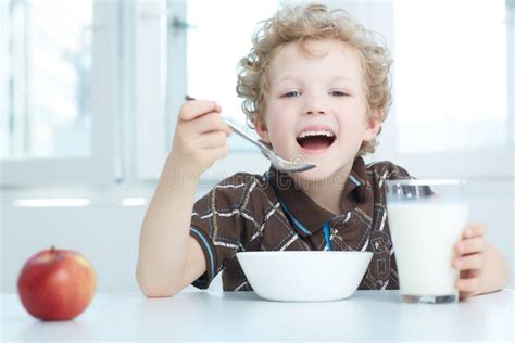 Happy Smiling Boy Eating Cereal while Having Breakfast in the Kitchen. Stock Image - Image of ...