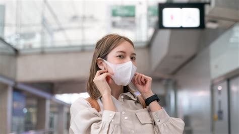 La mujer asiática usa máscaras mientras viaja a la terminal del