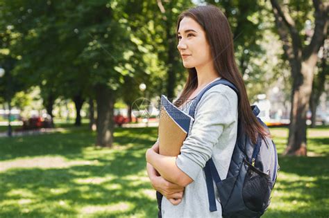 迷人的微笑女学生在户外公园里放着书高清图片下载 正版图片503602905 摄图网