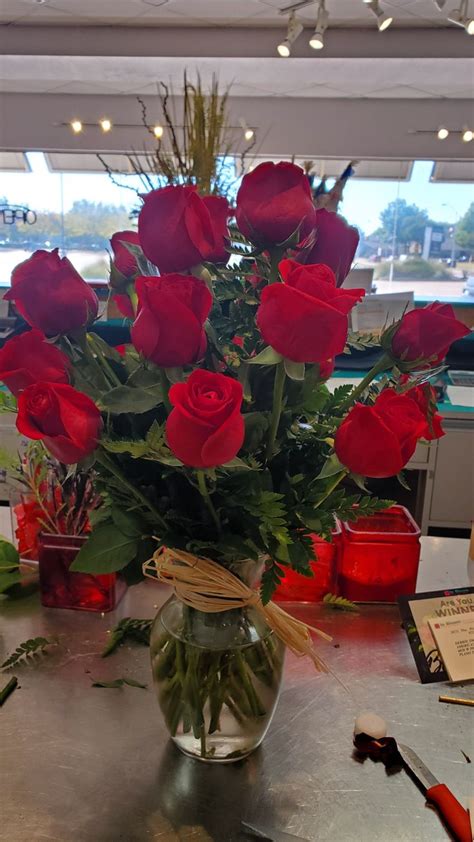 A Vase Filled With Red Roses Sitting On Top Of A Table Next To Other Items