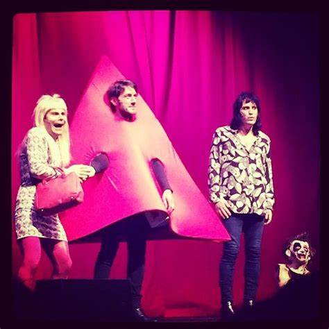 Three People Standing On Stage In Front Of A Pink Object