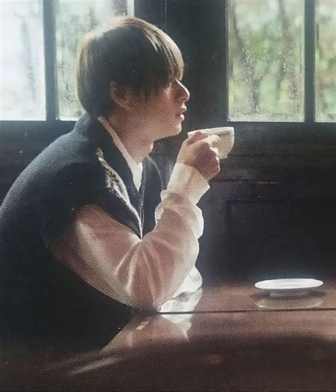 A Woman Sitting At A Table Drinking From A Cup With Her Arm Wrapped