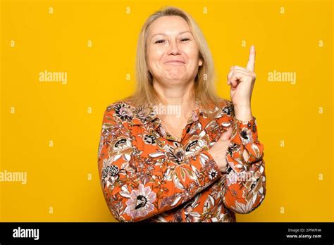 Caucasian Blonde Woman In A Patterned Dress Raising Her Index Finger Smiling She Had A Great