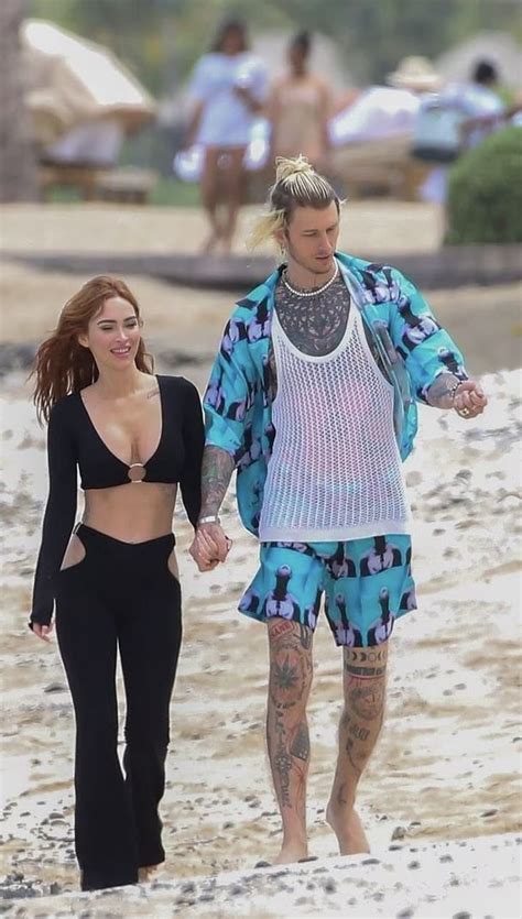 A Man And Woman Walking On The Beach With Their Hands In Each Other S