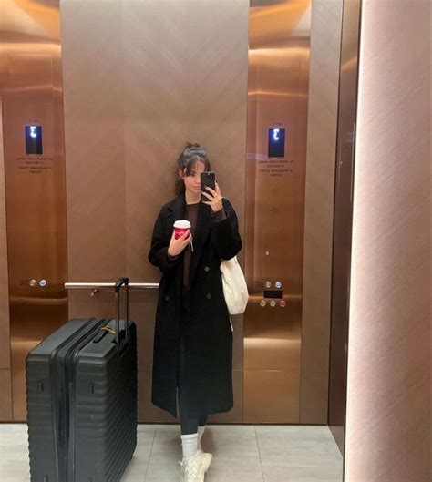 A Woman Taking A Selfie In An Elevator With Her Luggage And Cup Of Coffee