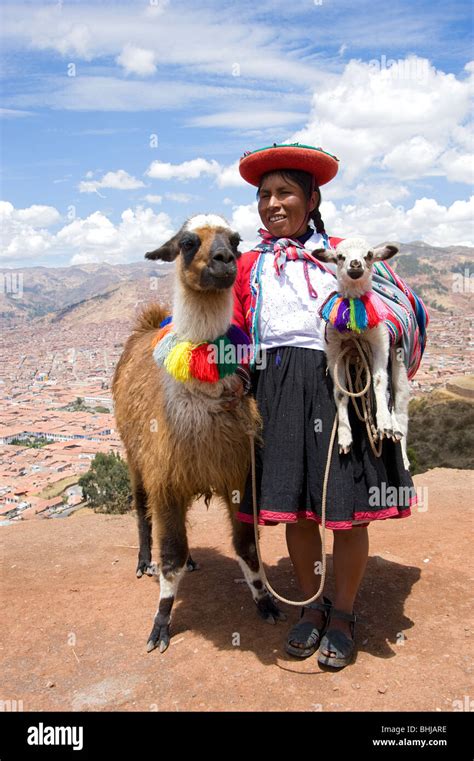 A Woman Dressed In Traditional Peruvian Clothing Posing With A Llama