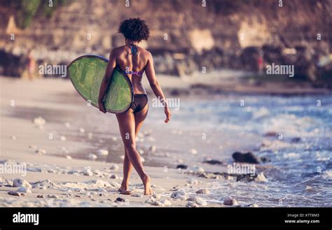 Surfer Girl With Afro Hairstyle Walking With Surfboard On The Padang