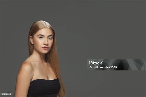 Beautiful Model With Long Smooth Flying Blonde Hair Isolated On Dark