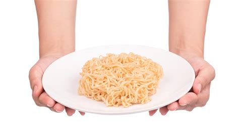 Mano sujetando cocidos de fideos instantáneos en plato aislado sobre