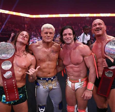 Three Men Standing Next To Each Other Holding Wrestling Belts