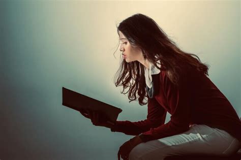 Premium Photo Side View Of Woman Reading Book While Sitting Against Wall