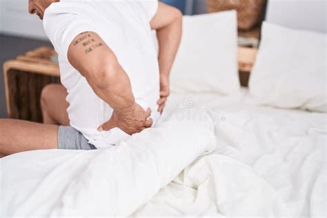 Middle Age Grey Haired Man Suffering For Backache Sitting On Bed At