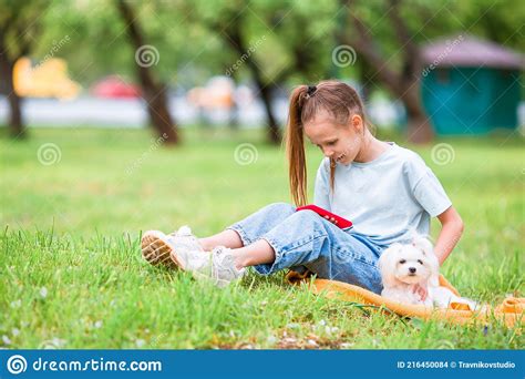 Petite Fille Souriante Jouant Et Serrant Chiot Dans Le Parc Photo Stock