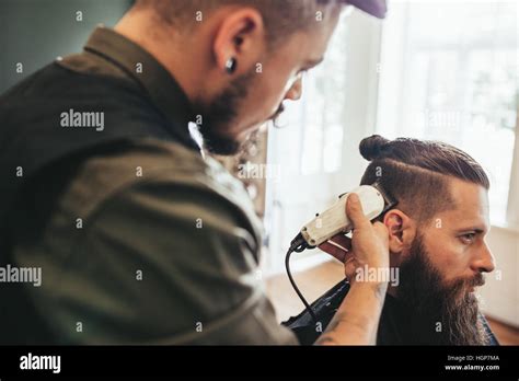 Beard man getting haircut at barber shop. Hairdresser cutting hair of ...